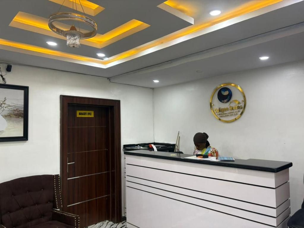 A reception area with a desk, a framed picture on the wall, and a chandelier.