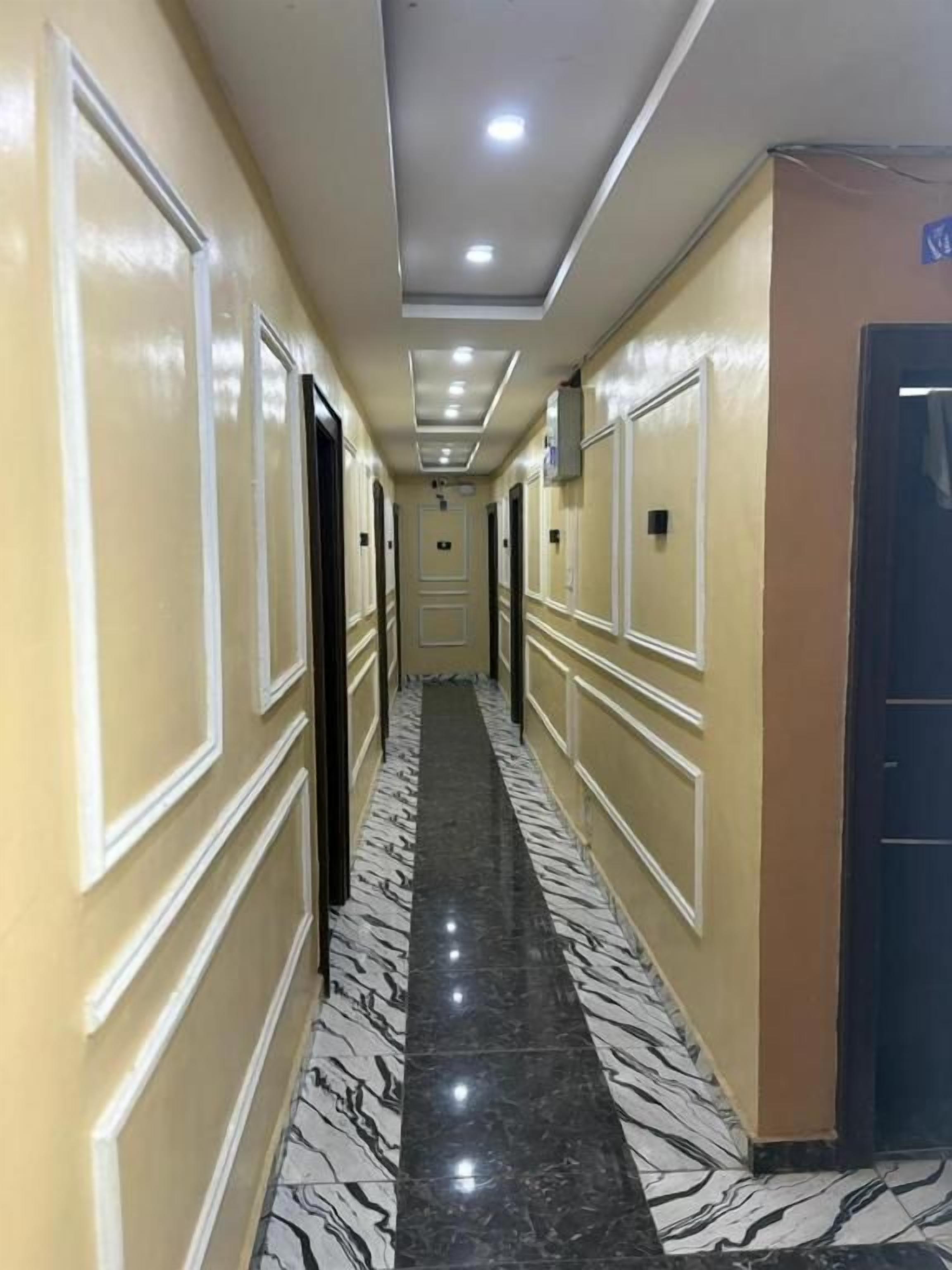 A hotel hallway with a marble floor, cream walls, and doors leading to rooms.