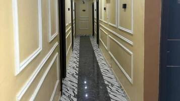 A hotel hallway with a marble floor, cream walls, and doors leading to rooms.