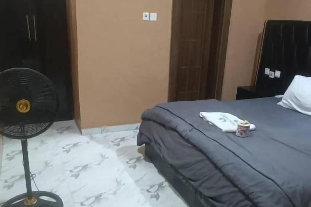 A bedroom with a bed, a fan, and a door.