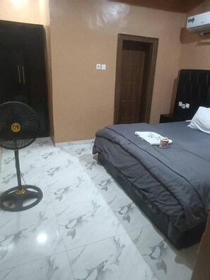 Quarto com cama, ventilador e porta.