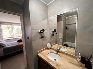 A modern bathroom with a large mirror, two sinks, and a shower. - COZY, WARM, FLEXIBLE, CENTRAL, 2 bedrooms, 2 bathrooms, 3 living areas + parking (Puerto Varas)