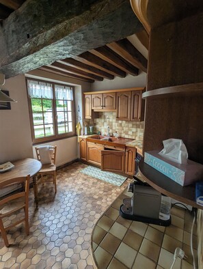 A kitchen with wooden cabinets, a tiled floor, and a window with a view of greenery. - Family home between the Loire Valley and Sologne (Lailly-en-Val)