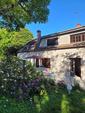 A two-story house with a garden, a patio with chairs, and a chimney. - Family home between the Loire Valley and Sologne (Lailly-en-Val)