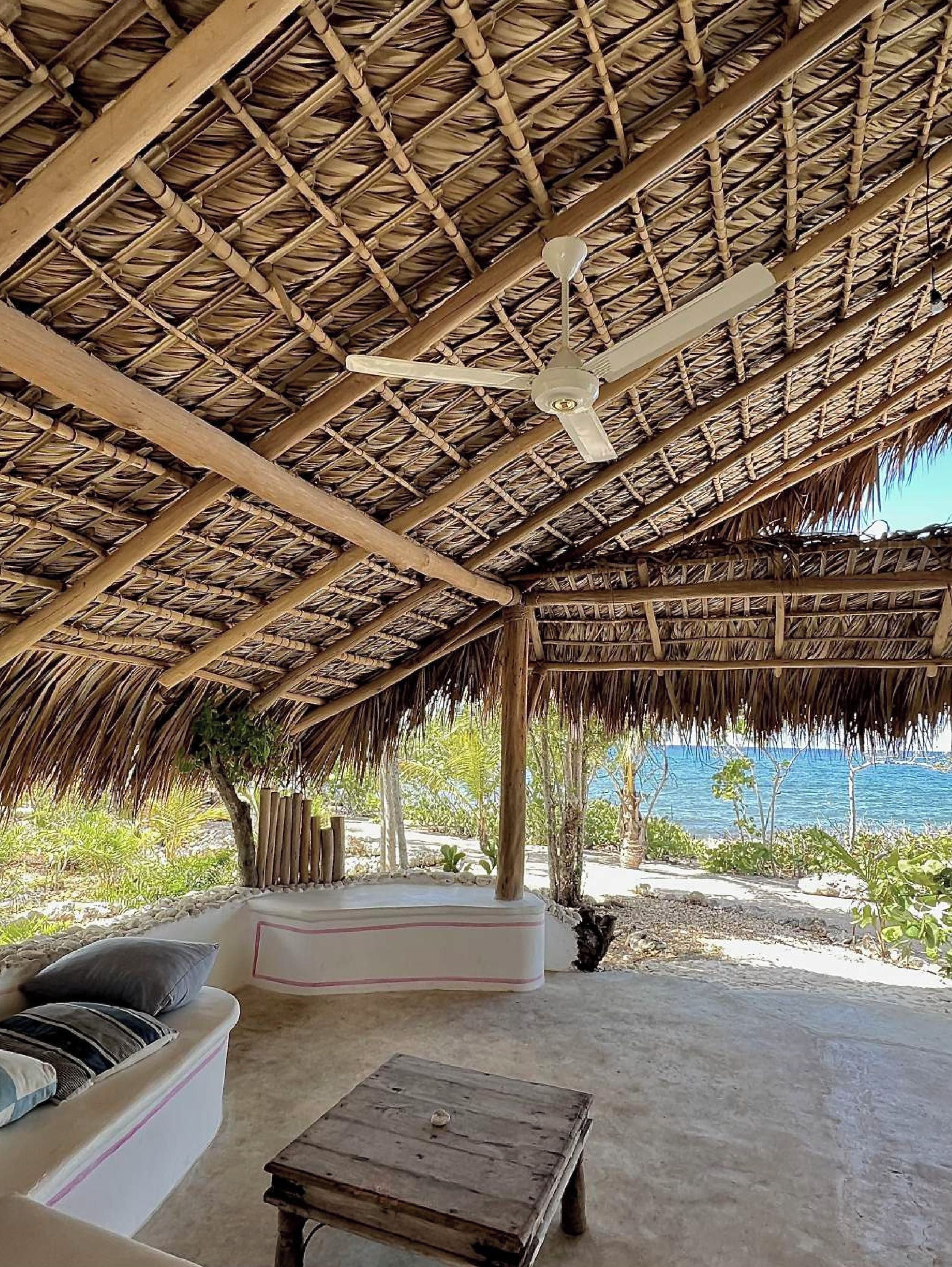 A covered outdoor seating area with a ceiling fan, a sofa, and a table.