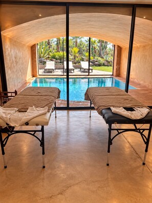 A spa room with a pool, two massage tables, and a view of the outdoor pool area. - Villa Malika Private Luxury Villa Marrakech (Marrakech)