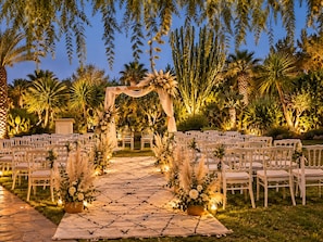 An outdoor wedding venue with a paved aisle, white chairs, and a floral archway. - Villa Malika Private Luxury Villa Marrakech (Marrakech)