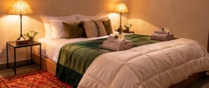 A neatly made bed with a green and white duvet, two bedside lamps, a small table with a vase and a tissue box, and a rolled towel on the bed. - Villa Malika Private Luxury Villa Marrakech (Marrakech)