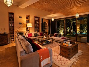 A spacious living room with a sofa, armchairs, a coffee table, and bookshelves.