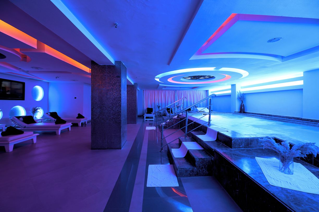 A modern hotel lobby with a stage, seating area, and a staircase.