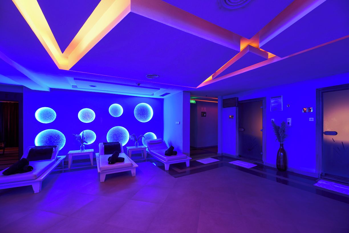 Ein Wellnessbereich mit Massagesesseln, einer Rezeption und einer Wand mit beleuchteten, kugelförmigen Dekorationen.