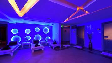 Ein Wellnessbereich mit Massagesesseln, einer Rezeption und einer Wand mit beleuchteten, kugelförmigen Dekorationen.