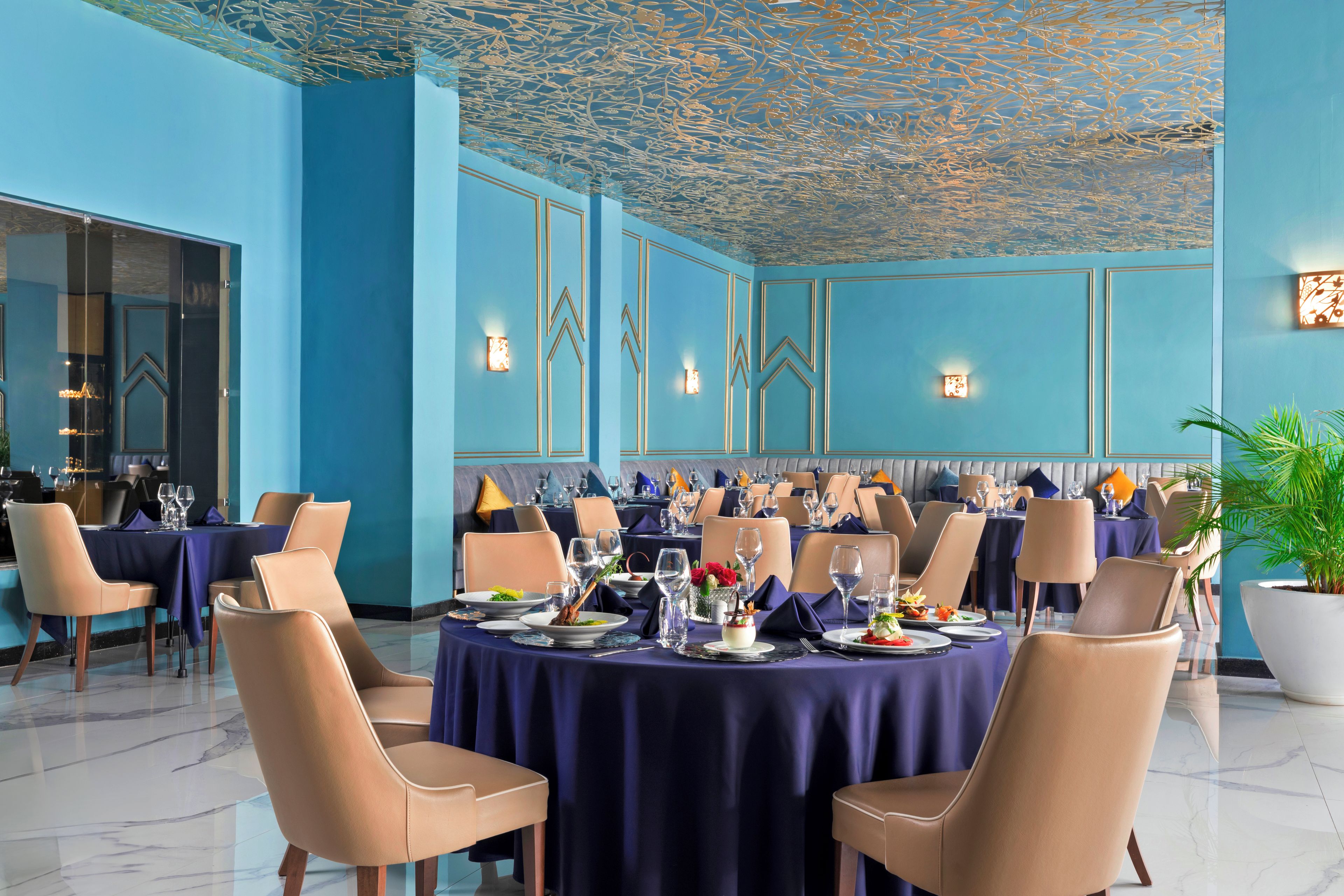 Un restaurante con mesas redondas, sillas y una decoración azul.