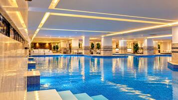 Una amplia piscina cubierta con varias zonas de estar y un diseño moderno.