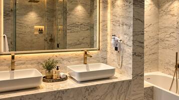A modern bathroom with two sinks, a large mirror, and a bathtub.