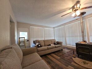 A living room with a sectional sofa, a fireplace, and a ceiling fan. - Fantastic 4-bedroom house with AC in charming Marcellus (Marcellus)