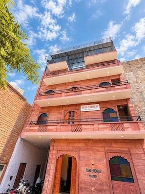 Un edificio de varios pisos con balcones, un letrero que dice 'Rang-E-Mehran Heritage' y un cielo despejado.