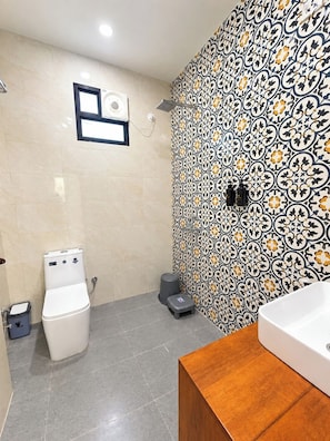 Un baño con inodoro, bidé y lavabo con tocador de madera.