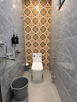 Een badkamer met toilet, bidet en een emmer.