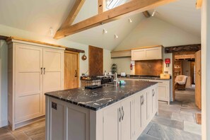 A spacious kitchen with a large island, white cabinetry, and a stone floor. - Scugdale -  a holiday cottage that sleeps 4 guests  in 2 bedrooms (Hartoft)
