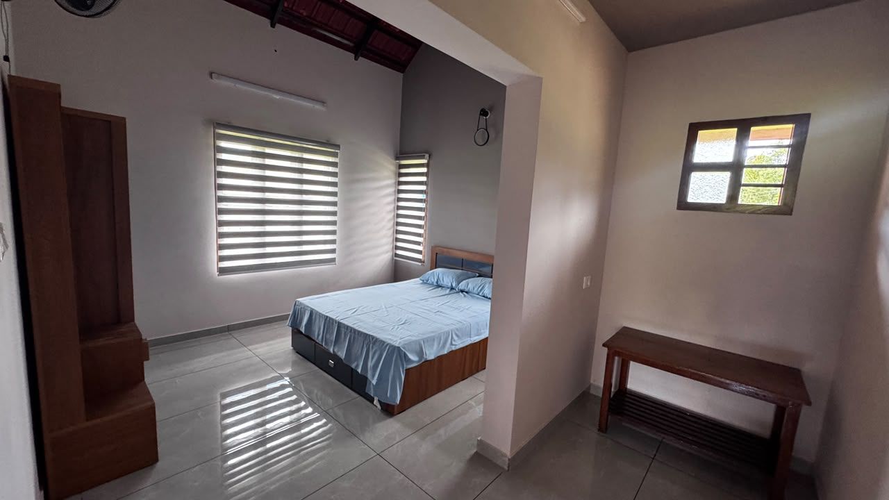 Een slaapkamer met een bed, twee ramen, een bankje en een trap.