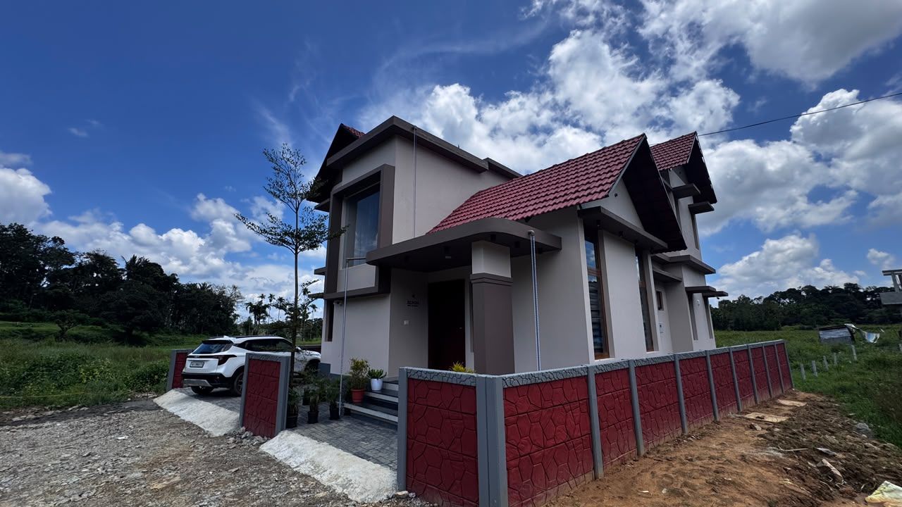 A modern two-story house with a red-tiled roof, a paved driveway, and a red fence.