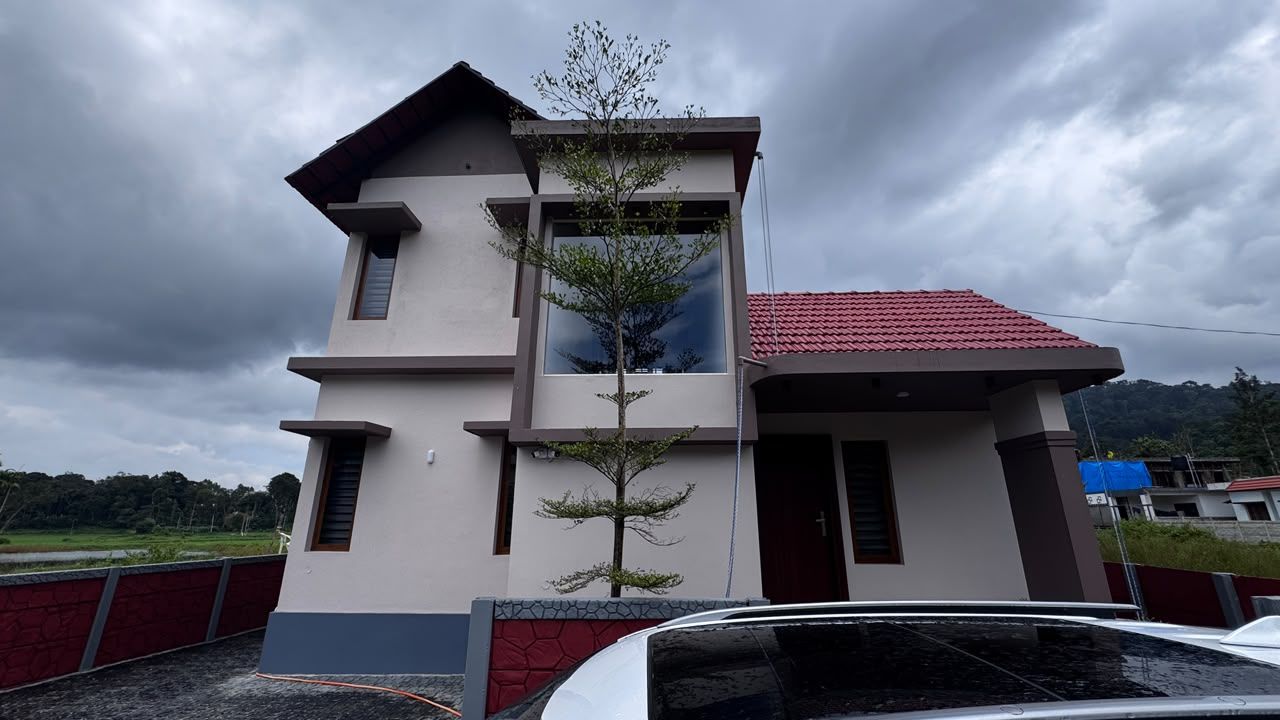 A two-story building with a red-tiled roof, a small tree in front, and a car parked in front.