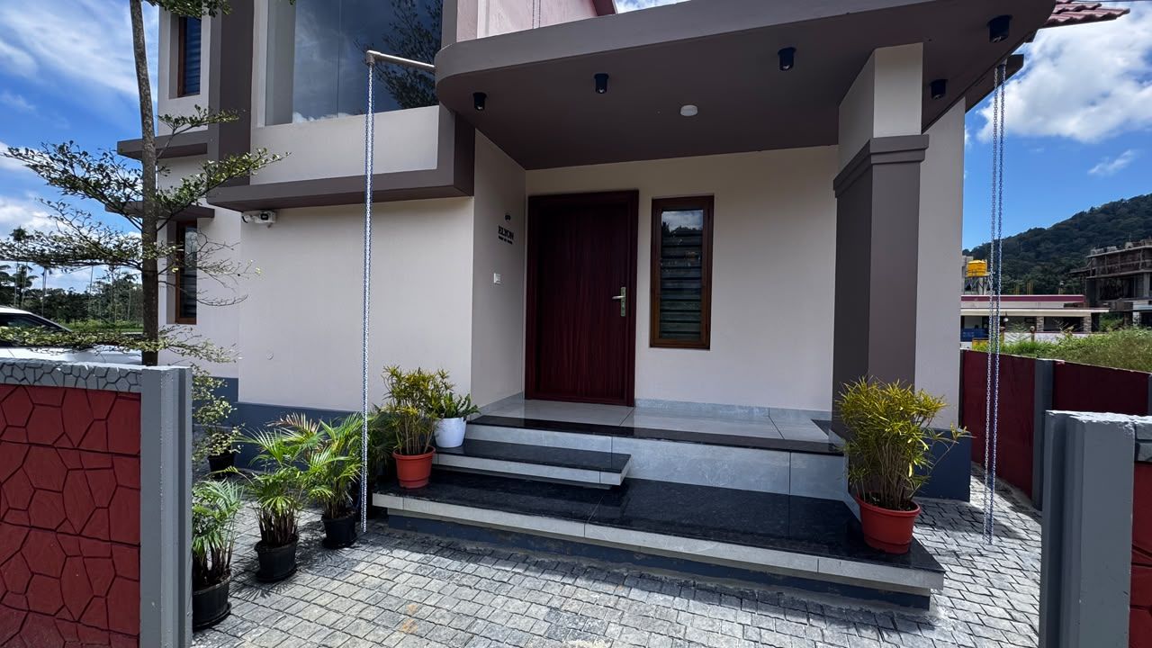 A modern building with a red door, potted plants, and a staircase leading to the entrance.