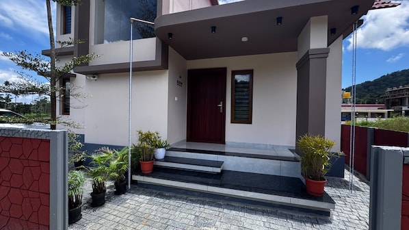 A modern building with a red door, potted plants, and a staircase leading to the entrance.