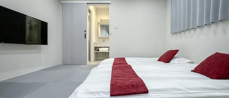 A hotel room with a large bed, a flat-screen TV, and a bathroom visible through an open door.