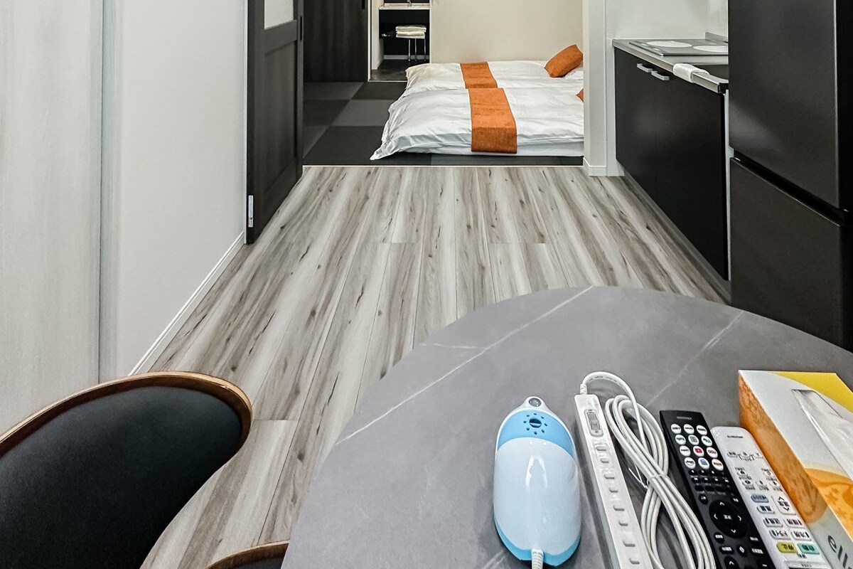 A hotel room with a bed, a desk with a computer, a microwave, and a refrigerator.