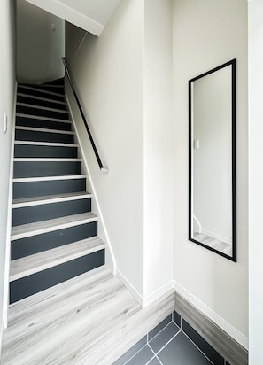 A staircase with a handrail, a wall-mounted mirror, and a tiled floor. - HANASTAY HIKARI (Osaka)