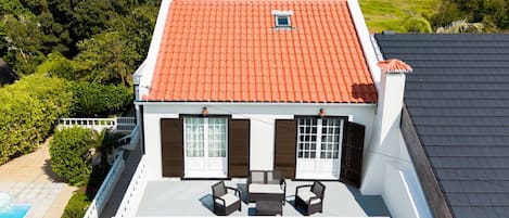 A two-story house with a red-tiled roof, a swimming pool, and a view of the ocean.