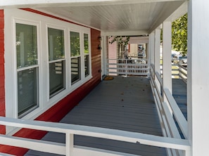 A covered porch with a wooden deck, white railings, and a red exterior wall. - Perfect for Groups! 4-Bedroom Home Near the Waterfront + Dining (Washington)