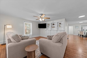 A spacious living area with a ceiling fan, a flat-screen TV, and a kitchen in the background. - Perfect for Groups! 4-Bedroom Home Near the Waterfront + Dining (Washington)