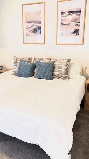 A bedroom with a bed, pillows, a nightstand, and two framed pictures on the wall. - Florida Retreat in Amenity-Rich Golf & Country Club Community (Bonita Springs)