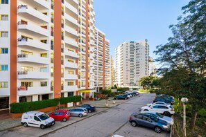 A multi-story residential building with balconies, a parking lot, and a clear sky. - 5 minute walk from Praia da Rocha, Wifi, AC, next to supermarkets and the Marina (Portimão)