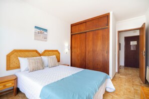A bedroom with a bed, wooden wardrobe, and a wall-mounted picture. - 5 minute walk from Praia da Rocha, Wifi, AC, next to supermarkets and the Marina (Portimão)
