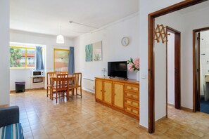 A living room with a dining area, a television, and a clock on the wall. - 5 minute walk from Praia da Rocha, Wifi, AC, next to supermarkets and the Marina (Portimão)