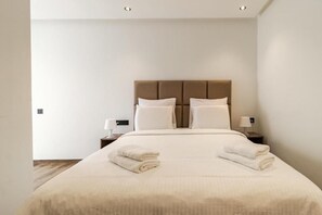 Ein Hotelzimmer mit einem großen Bett, zwei Nachttischen und einer neutralen Farbgestaltung.