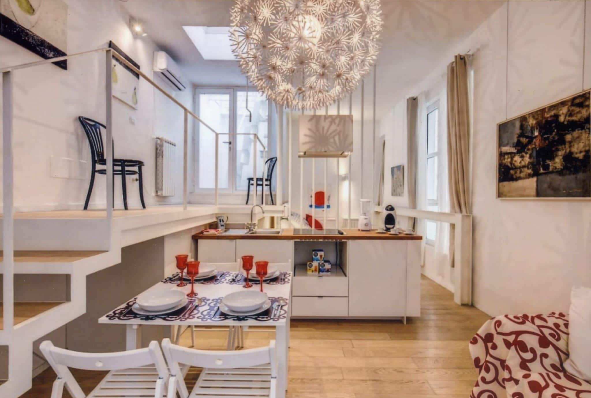 A modern interior with a dining area, kitchen, and a large decorative light fixture.