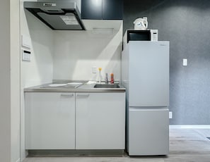 Een kleine keuken met een koelkast, een magnetron en een spoelbak.