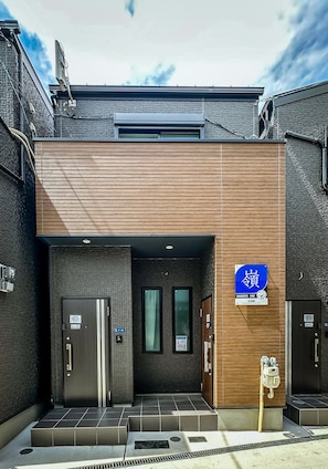 A building with a wooden facade, two doors, and a blue sign with Japanese characters. - HANASTAY MINE (Osaka)