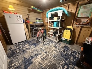 Eine kleine Küche mit einem Kühlschrank, einem Fahrrad und einer Regaleinheit mit Aufbewahrungsboxen.
