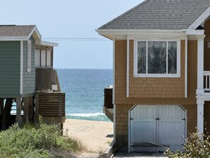 Una propiedad frente al mar con una casa de dos pisos, un garaje y una estructura de madera.