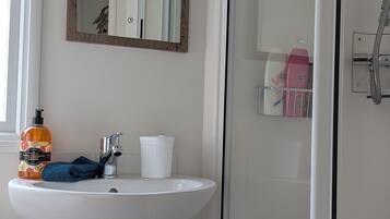 Un bagno con lavandino bianco, specchio e zona doccia.