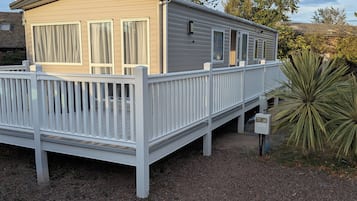 A mobile home with a deck and a utility box.