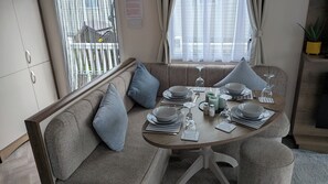 A dining area with a round table set for four, including plates, glasses, and cutlery. - Holiday Home With Access to Leisure Facilities (Dunbar)