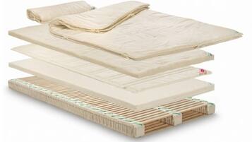 A stack of mattresses with a wooden frame and a folded blanket on top.