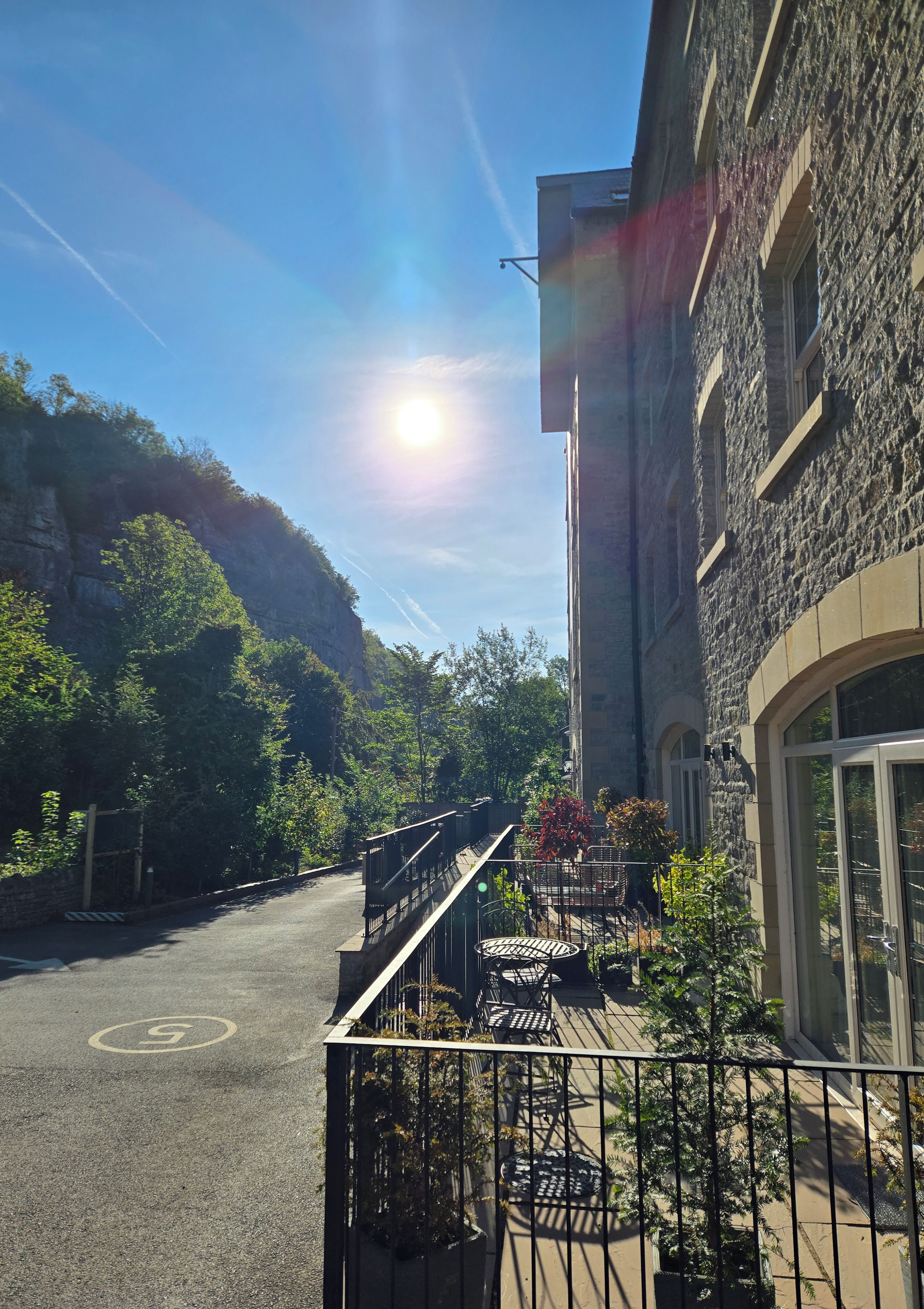 A building with a stone facade, a balcony with outdoor seating, and a clear sky.